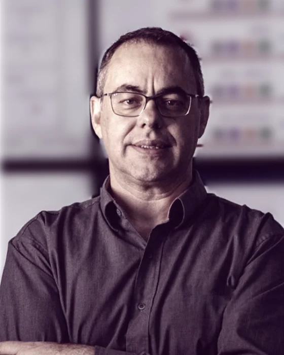 Miguel Rossato de braços cruzados diante de painéis de indicadores de gestão.